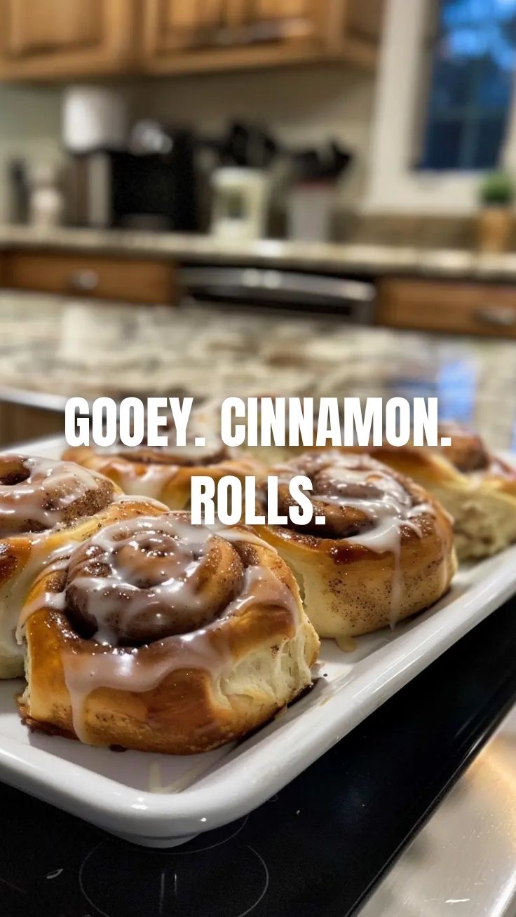 Freshly baked homemade cinnamon rolls with icing on a cooling rack.