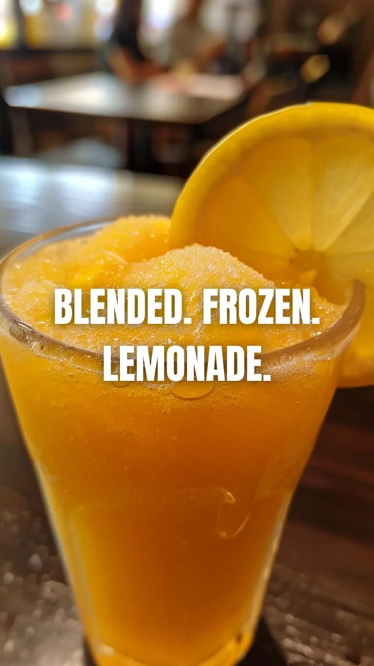 A tall glass of icy frozen lemonade with a lemon slice garnish