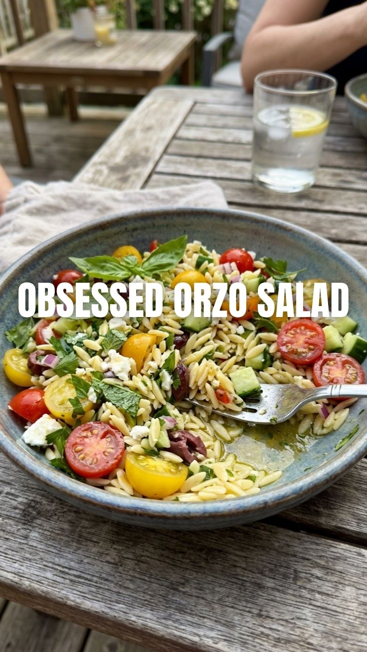 A vibrant Orzo Salad, perfect for summer gatherings, in a large white bowl.