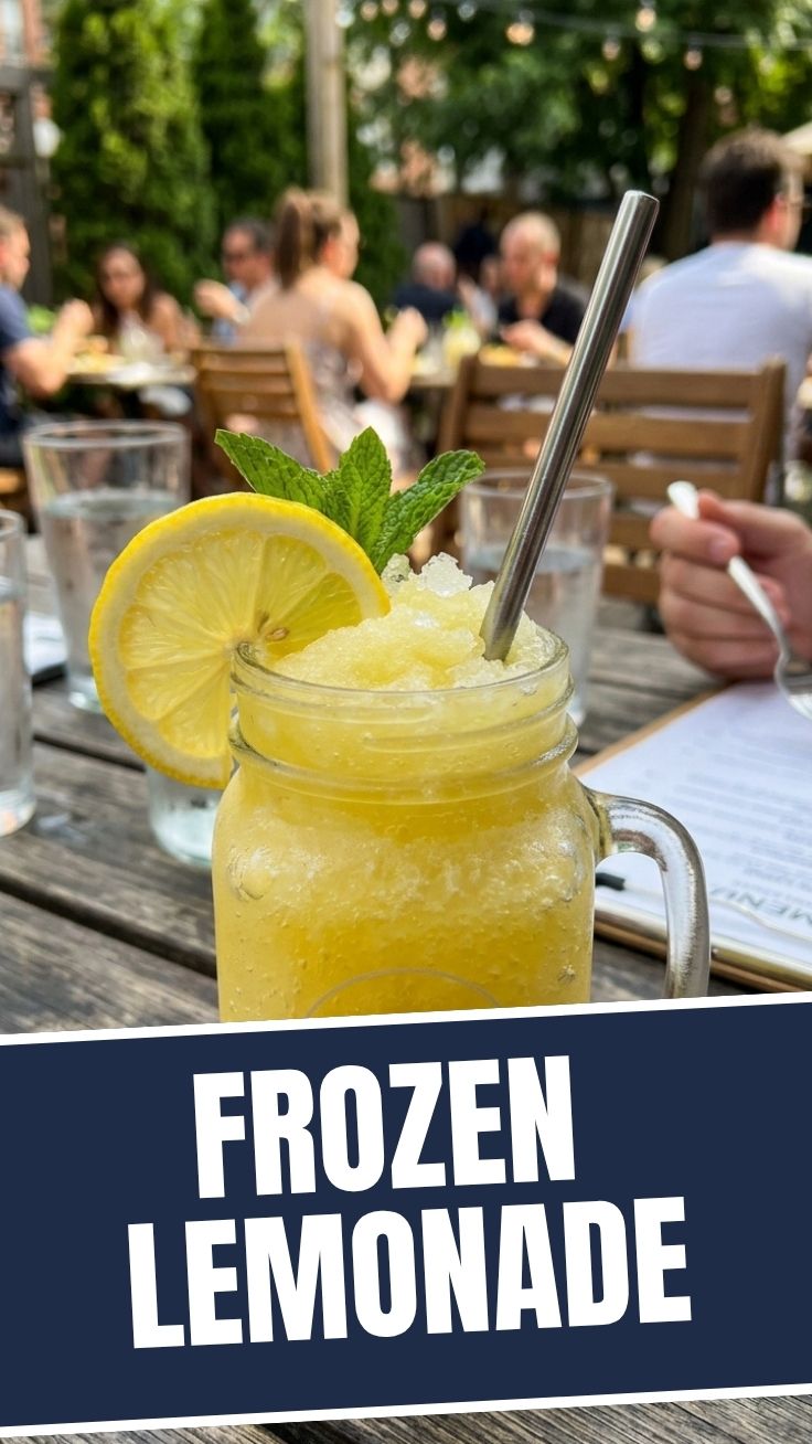 A tall glass of icy frozen lemonade with a lemon slice and straw, shot close up.
