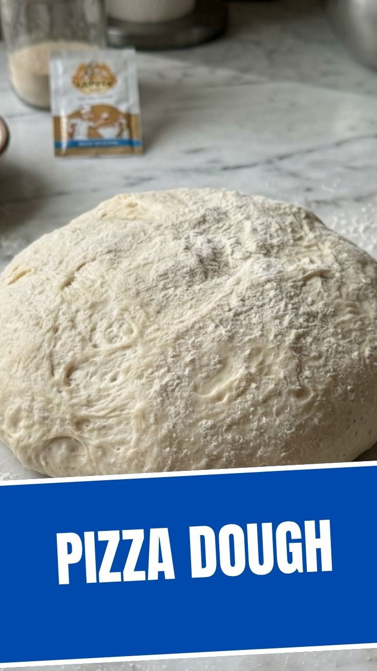 A perfect ball of pizza dough resting on a floured surface, ready for kneading.