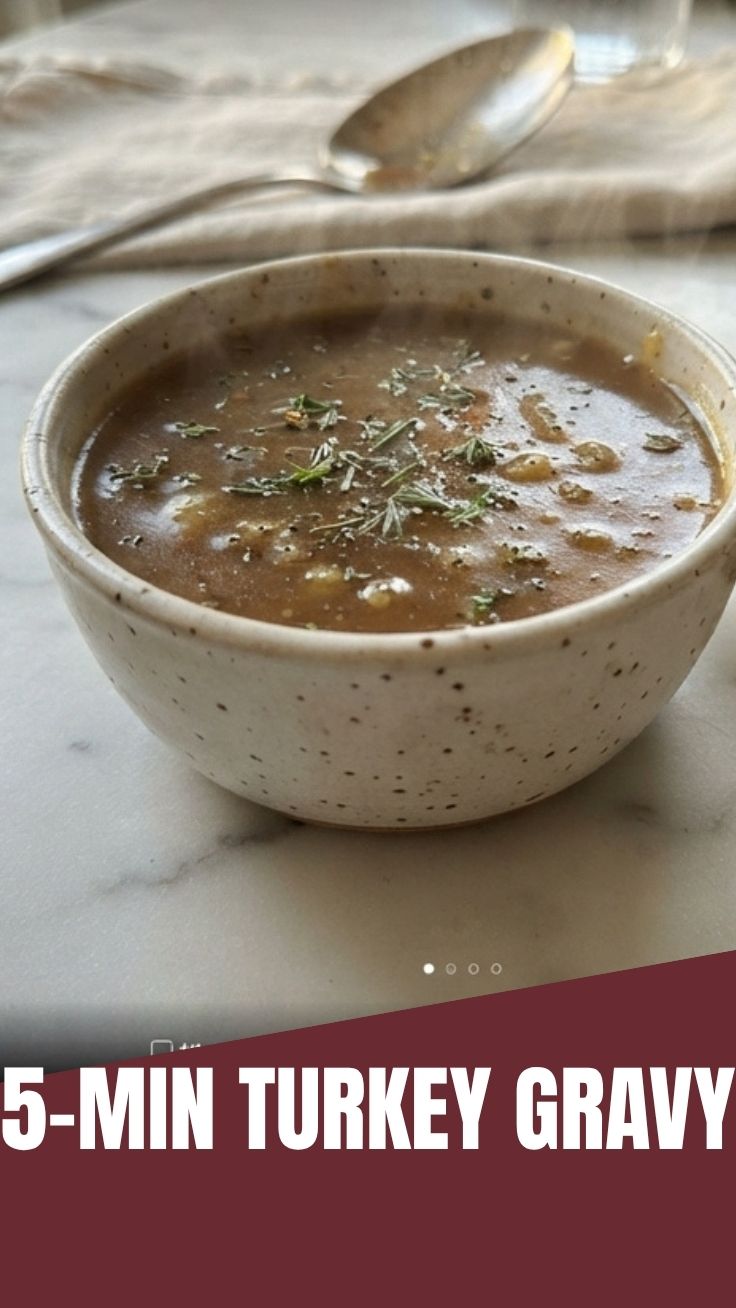 A close-up of thick, savory turkey gravy in a white gravy boat.